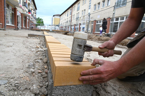 Bild vergrößern: Holzhammer schlgt auf gelben Klinker: Das Veltener Band wird auf dem Marktplatz gesetzt.