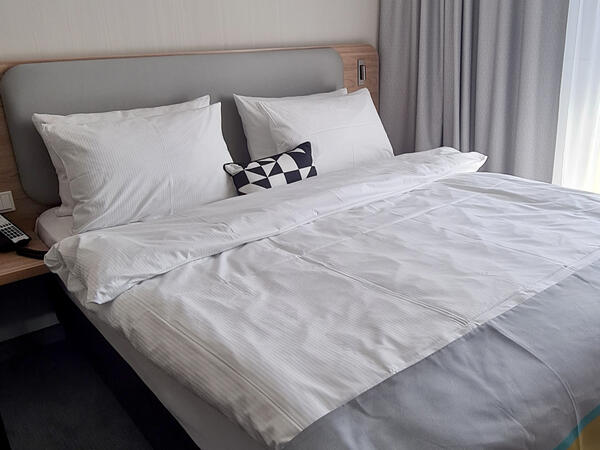 Bild vergrößern: Ein Bett im Hotelzimmer.